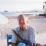 Senior adult enjoying a sunny day on a beach with a serene sea backdrop.